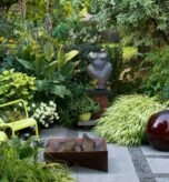Compact courtyard garden with vertical planters and wooden bench in soft natural light