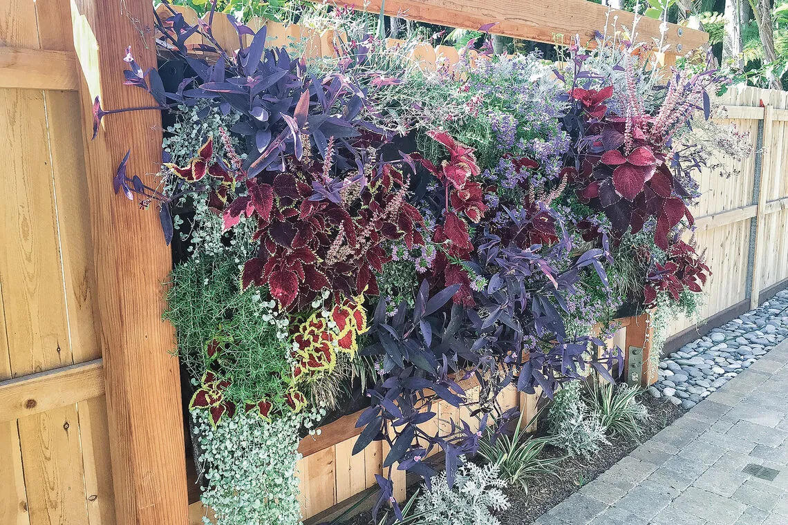 Fabric pocket planter with herb seedlings hanging on a brick balcony wall.